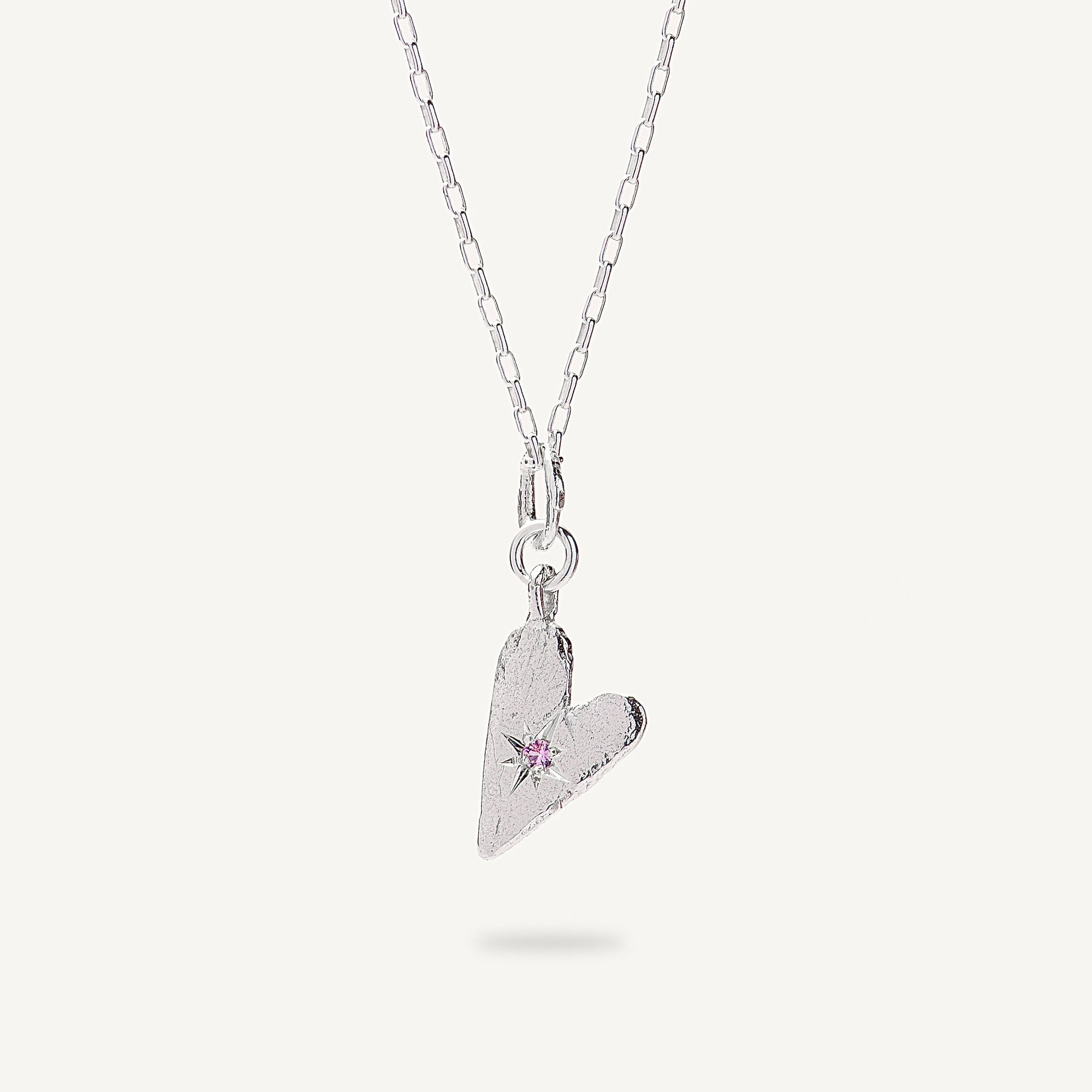 Silver heart-shaped pendant necklace with a pink gemstone on a white background