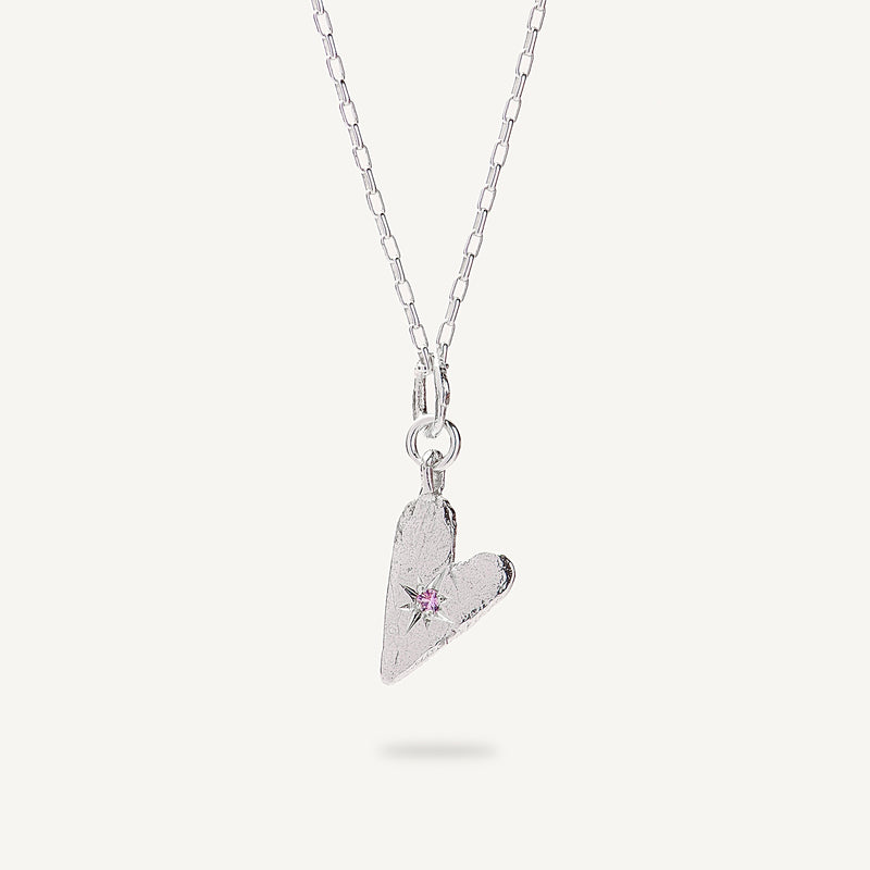 Silver heart-shaped pendant necklace with a pink gemstone on a white background