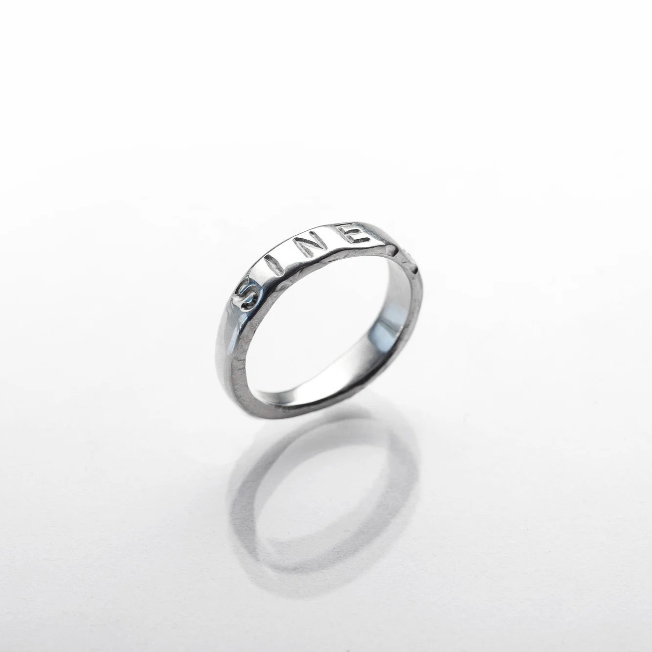 Silver ring with 'Infinity' engraving on a white background