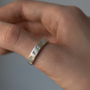 Hand wearing a silver ring on a plain background