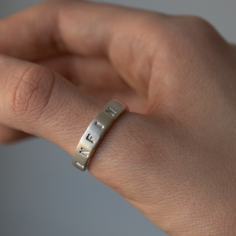 Hand wearing a silver ring on a plain background