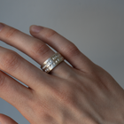 Hand wearing a silver ring on a plain background