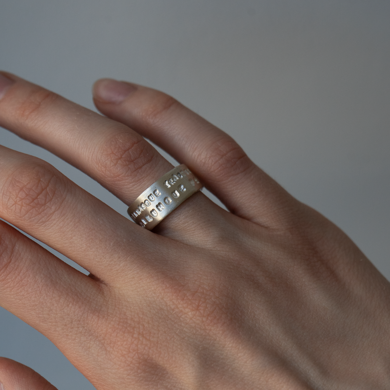 Hand wearing a silver ring on a plain background