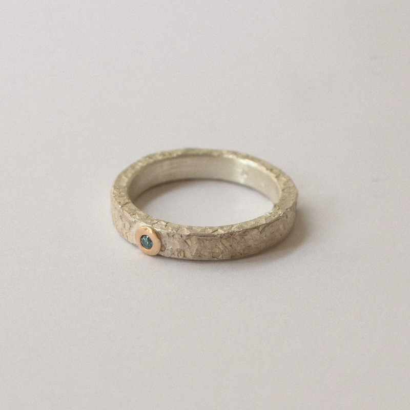 Silver ring with blue diamond on a light gray background