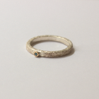Silver ring with a blue diamond gemstone on a light gray background