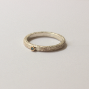 Silver ring with a blue diamond gemstone on a light gray background
