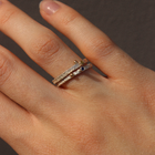 Hand wearing a silver ring with a blue sapphire on a neutral background