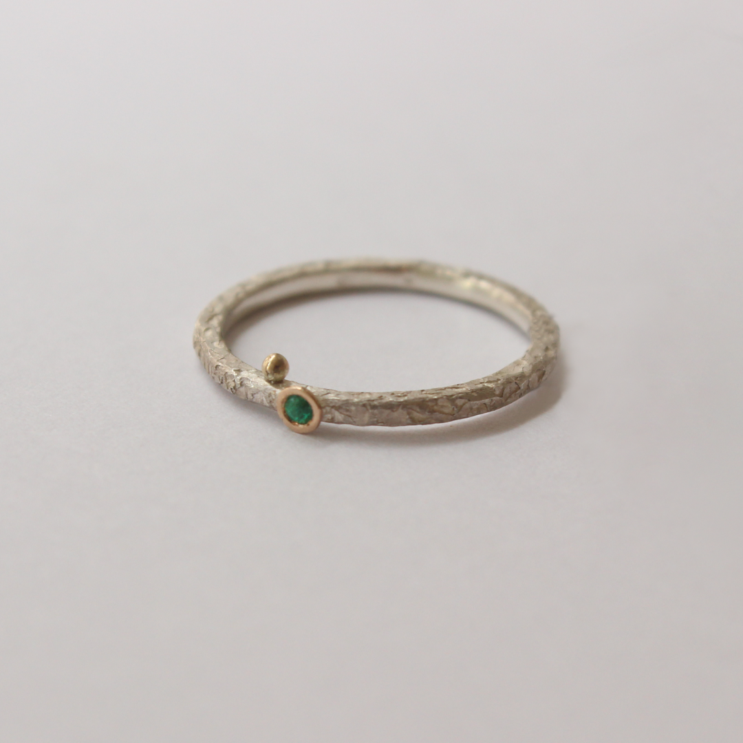 Silver ring with emerald on a light gray background