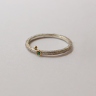 Silver ring with emerald on a light gray background