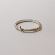 Silver ring with emerald on a light gray background