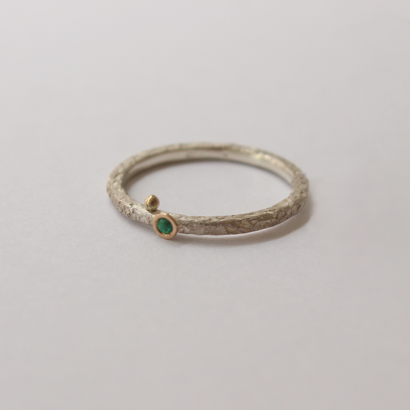 Silver ring with emerald on a light gray background