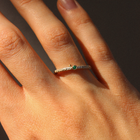 Close-up of a hand wearing a ring with a green emerald on a dark background