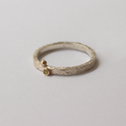 Silver ring with a small gold gemstone on a light gray background