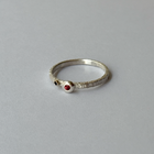 A silver ring with orange and blue sapphires set on the top, placed on a grey background.