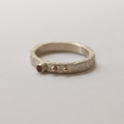 Silver ring with orange sapphire and gold accents on a light gray background