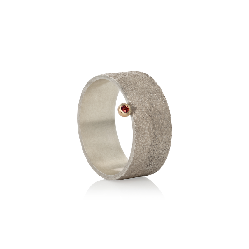 Silver ring with a red rubie on a white background