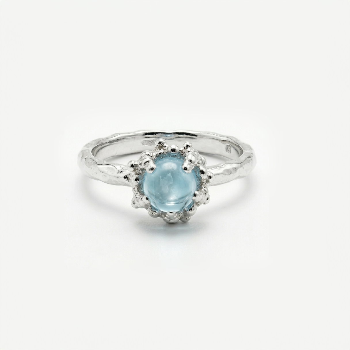 Silver ring with a light blue topaz on a white background