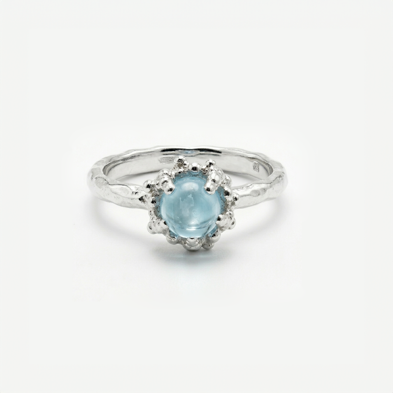 Silver ring with a light blue topaz on a white background
