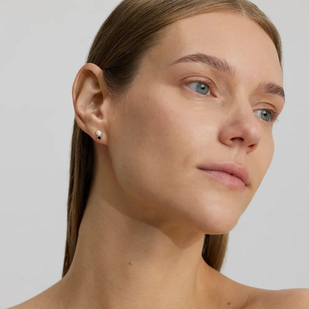 Close-up of a woman's face with silver stud earrings with black zirconium & pearl 