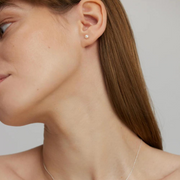 A woman wearing a single silver earring with a pearl, designed to be subtle and elegant.