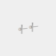 A pair of silver stud earrings with a round pearl attached to silver string, against a white background.
