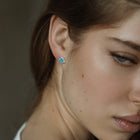 Close-up of a woman wearing a blue topaz earring with a blurred background