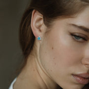 Close-up of a woman wearing a blue topaz earring with a blurred background