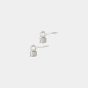Pair of silver earrings with freshwater pearls and white zirconium stones on a light gray background