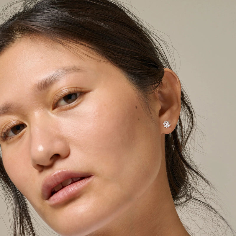 Close-up of a person wearing a diamond earring against a neutral background