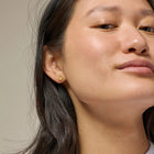 Close-up of a woman wearing gold earrings with a neutral background