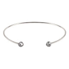 A thin white gold open cuff bangle bracelet with two small faceted grey diamonds at the ends, shown on a plain white background.