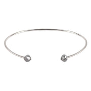 A thin white gold open cuff bangle bracelet with two small faceted grey diamonds at the ends, shown on a plain white background.