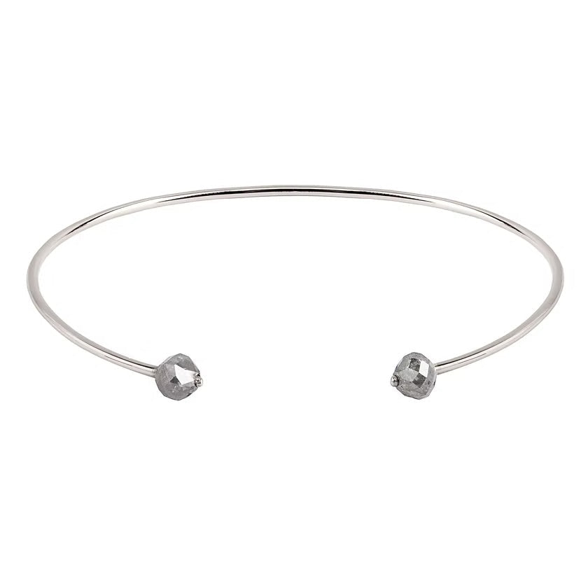 A thin white gold open cuff bangle bracelet with two small faceted grey diamonds at the ends, shown on a plain white background.