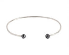 A thin white gold open cuff bangle bracelet with two small faceted grey diamonds at the ends, shown on a plain white background.