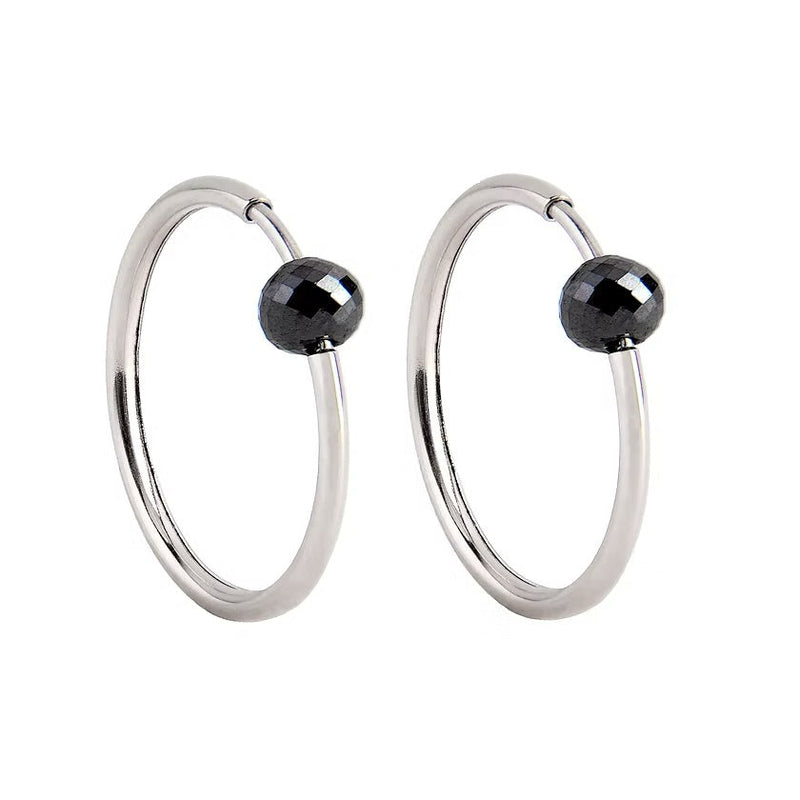 A pair of white gold hoop earrings with a small, faceted dark grey diamond bead attached near the top right of each hoop, shown against a plain white background.