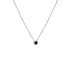 A delicate white gold chain necklace with a small bezel-set ocean blue diamond pendant, shown against a plain white background.