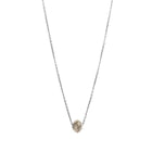 A delicate white gold chain necklace featuring a small, raw, faceted diamond pendant, shown against a solid white background.