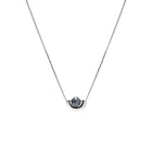 A delicate white gold chain necklace featuring a small, polished gold crescent-shaped setting holding a round, dark gray diamond, presented on a solid white background.