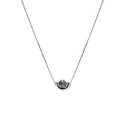 A delicate white gold chain necklace featuring a small, polished gold crescent-shaped setting holding a round, dark gray diamond, presented on a solid white background.