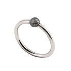A minimalist white gold ring featuring a single, small, round grey faceted diamond, shown on a plain white background.