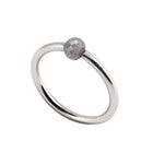 A minimalist white gold ring featuring a single, small, round grey faceted diamond, shown on a plain white background.