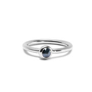 A white gold ring with a single faceted dark ocean blue gemstone in a bezel setting, shown on a clean white background.