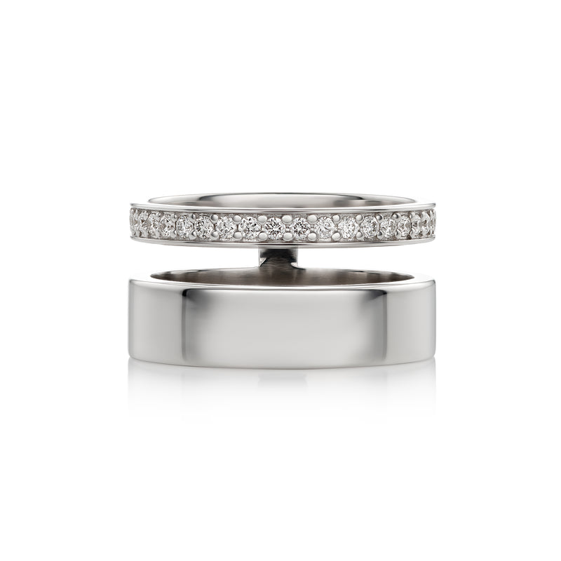 A polished white gold ring shown open, with one half featuring a row of clear pavé stones and the other half plain, on a white background.
