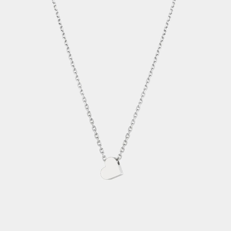 White gold heart-shaped pendant necklace on a light gray background