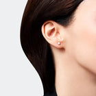 Close-up of a person wearing a classic stud earring crafted from 14k white gold, featuring brilliant diamond.