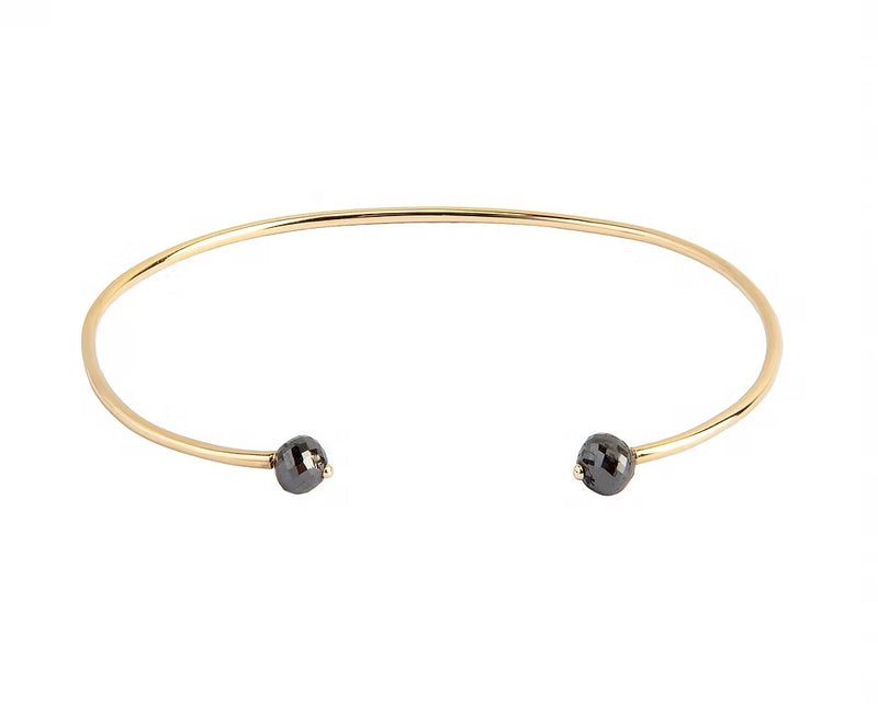 A thin yellow gold open cuff bangle bracelet with two small faceted grey diamonds at the ends, shown on a plain white background.