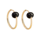 A pair of yellow gold hoop earrings with a faceted black gemstone dangling from the right side of each hoop, shown against a plain white background.