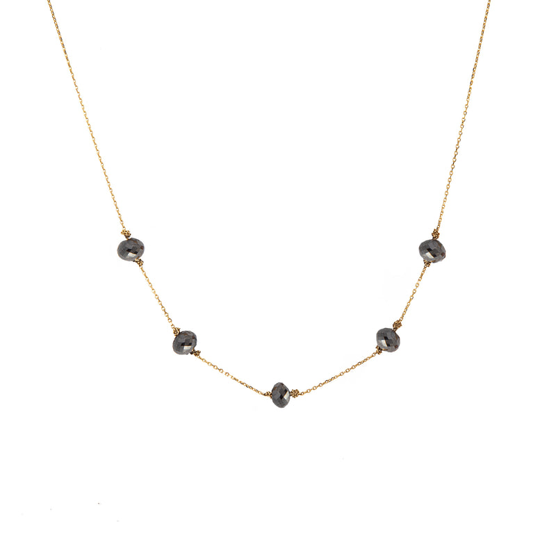 A delicate yellow gold chain necklace featuring five small, dark, faceted diamonds spaced along the front, displayed against a solid white background.