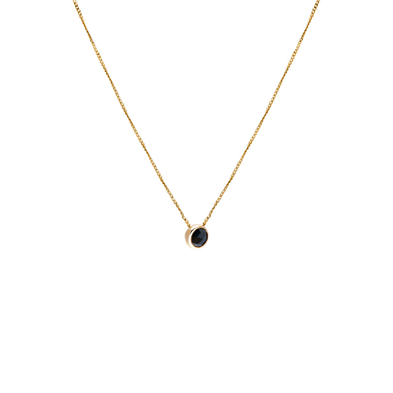 A delicate gold chain necklace with a small bezel-set ocean blue diamond pendant, shown against a plain white background.