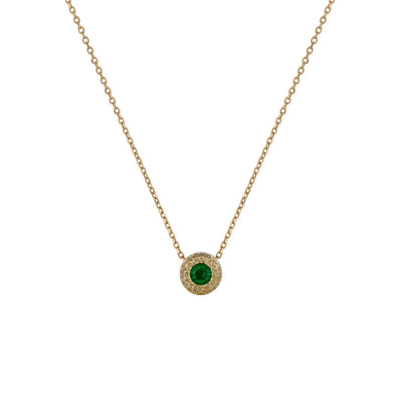 A delicate yellow gold chain necklace featuring a circular pendant with a central green emerald stone, set against a plain white background.